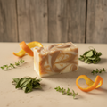 Patchouli and Orange handcrafted soap close up with orange peel, patchouli leaves, and greenery against a rustic wooden wall